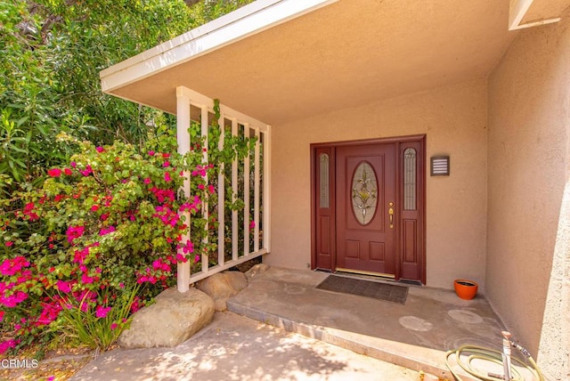 entrance to property with stucco siding and covered porch