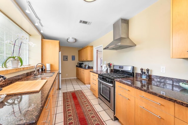 kitchen featuring exhaust hood, light tile patterned flooring, a sink, stainless steel range with gas cooktop, and visible vents