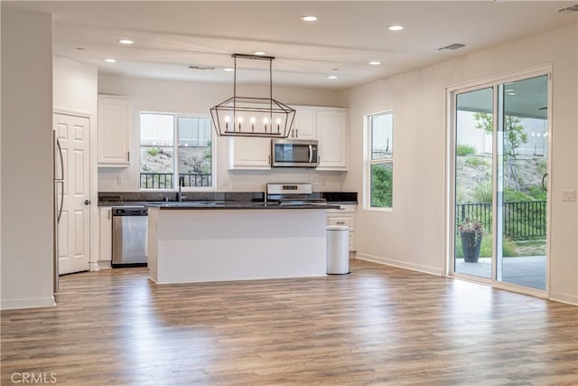 kitchen with dark countertops, appliances with stainless steel finishes, white cabinetry, and light wood-style floors