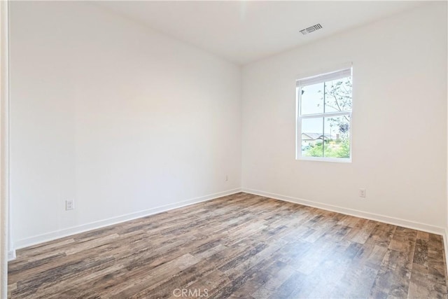 unfurnished room with baseboards, visible vents, and wood finished floors