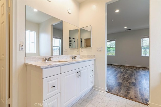 bathroom featuring baseboards, visible vents, a sink, and double vanity
