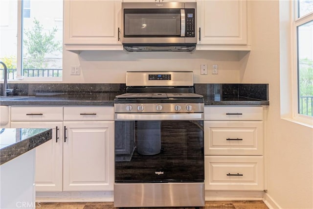 kitchen with a wealth of natural light, white cabinetry, and stainless steel appliances