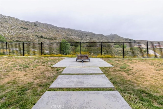 view of yard with a fire pit, a mountain view, a patio, and fence