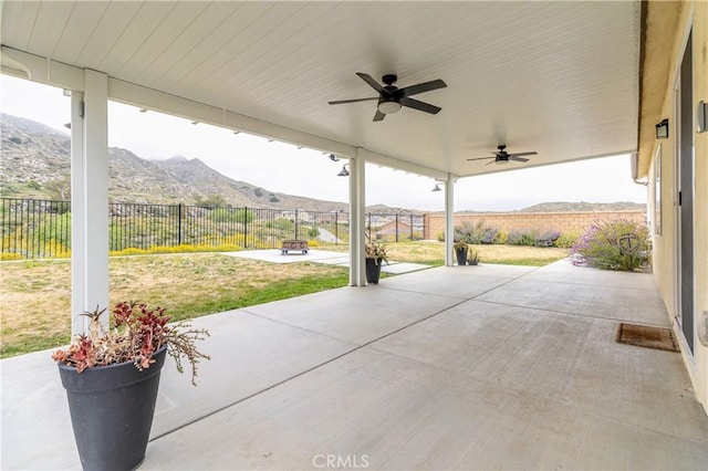 view of patio with a fenced backyard, a ceiling fan, and a mountain view