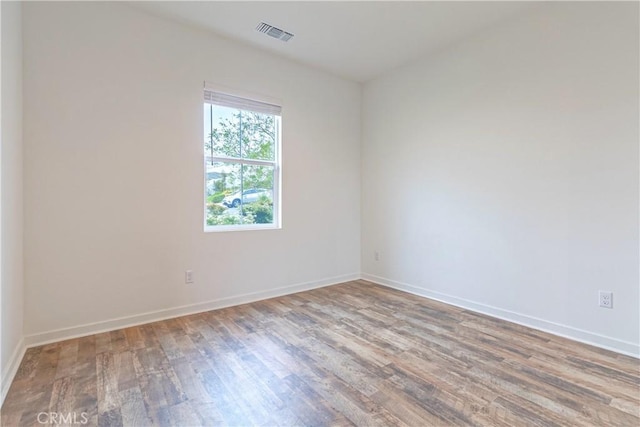 spare room featuring baseboards, visible vents, and wood finished floors