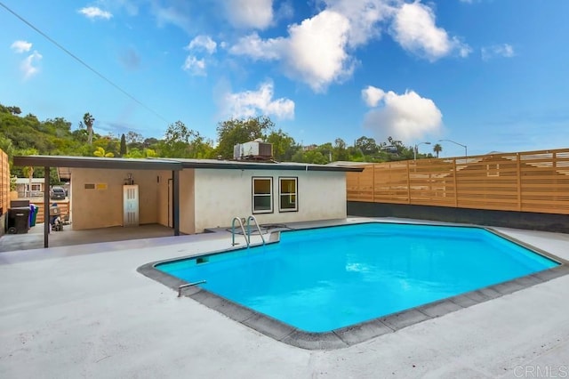 swimming pool with fence and a patio area