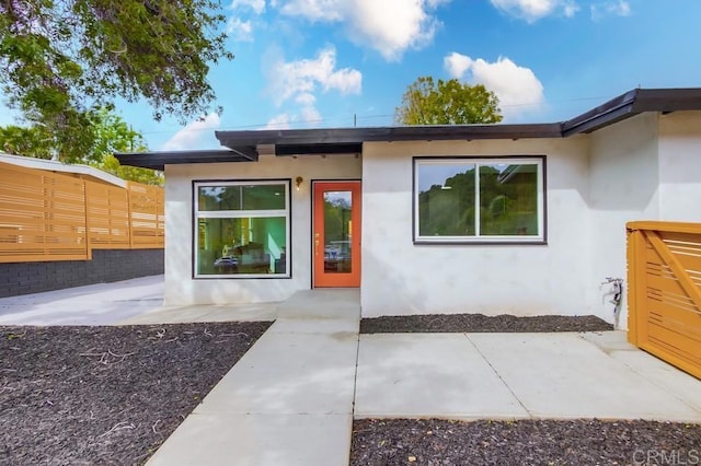 property entrance featuring stucco siding, a patio area, and fence