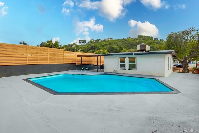 view of swimming pool with a patio area, fence, and cooling unit