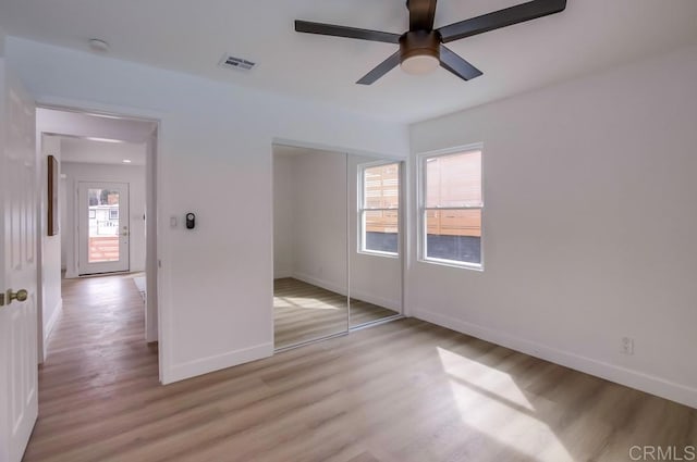 unfurnished bedroom featuring light wood-type flooring, baseboards, a closet, and a ceiling fan