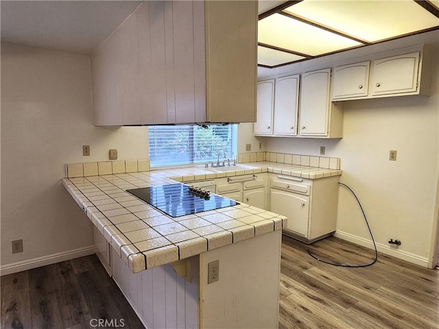 4872 Emerald Ave, La Verne, CA 91750 - kitchen with wood finished floors, black electric stovetop, a peninsula, and tile counters