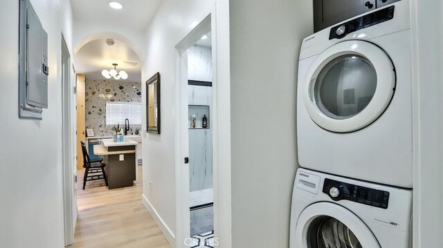 10301 Antigua St, Anaheim, CA 92804 - laundry room featuring a notable chandelier, stacked washer and clothes dryer, laundry area, light wood-style flooring, and baseboards