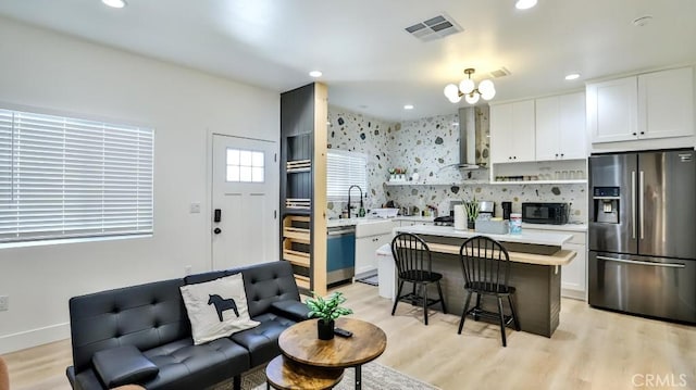 10301 Antigua St, Anaheim, CA 92804 - kitchen featuring stainless steel fridge, open shelves, black microwave, visible vents, and wall chimney exhaust hood