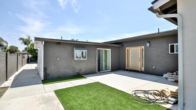 10301 Antigua St, Anaheim, CA 92804 - rear view of house with a patio area, a lawn, stucco siding, and fence