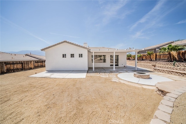 rear view of house featuring a patio, a tiled roof, an outdoor fire pit, stucco siding, and a fenced backyard