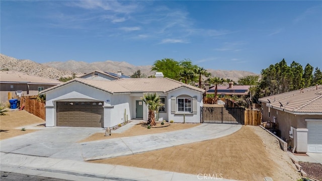single story home featuring a gate, a mountain view, a tiled roof, concrete driveway, and an attached garage