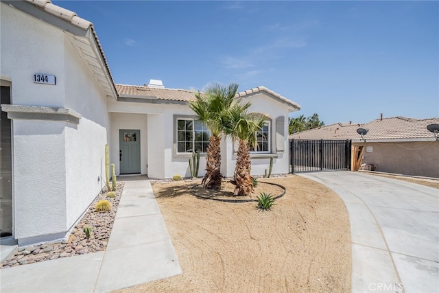 view of front of house with a gate, driveway, a tiled roof, stucco siding, and fence