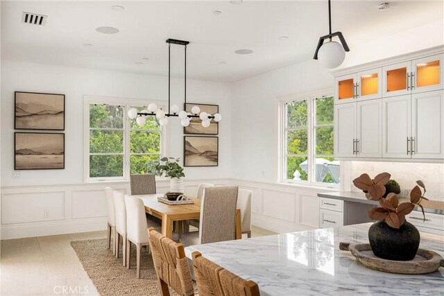 dining room with visible vents, wainscoting, a wealth of natural light, and a decorative wall