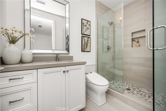 full bathroom featuring vanity, a stall shower, and toilet