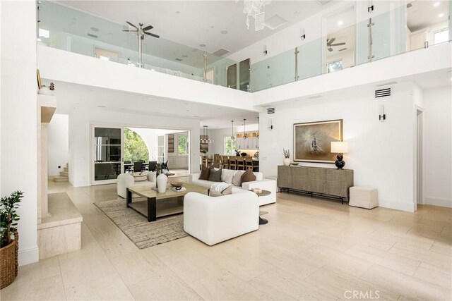 living area featuring baseboards, a high ceiling, and visible vents