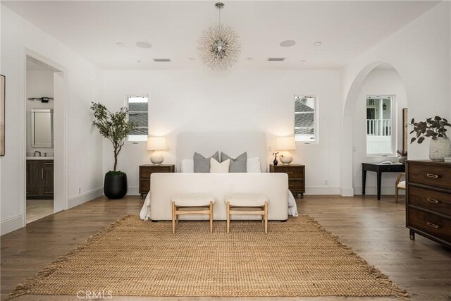 bedroom featuring arched walkways, baseboards, wood finished floors, and visible vents