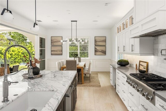 kitchen featuring plenty of natural light, a sink, glass insert cabinets, and stainless steel gas stovetop