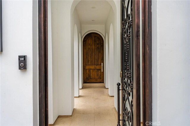 hall with light tile patterned floors and arched walkways
