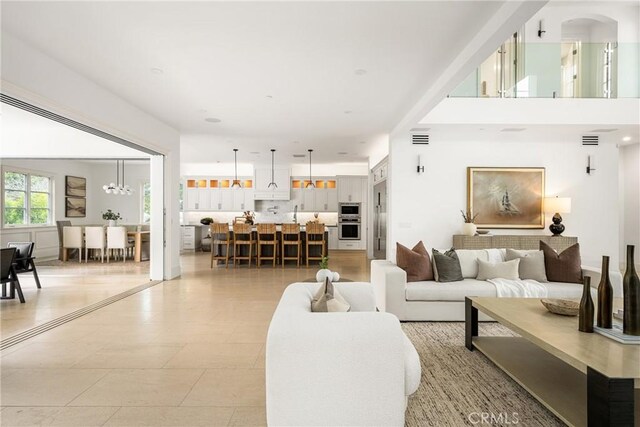 living room with arched walkways, a notable chandelier, and visible vents