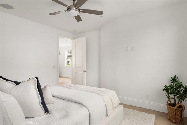 bedroom featuring a ceiling fan, baseboards, and light wood-style flooring