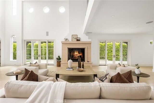 living area with visible vents, baseboards, a high ceiling, french doors, and a premium fireplace