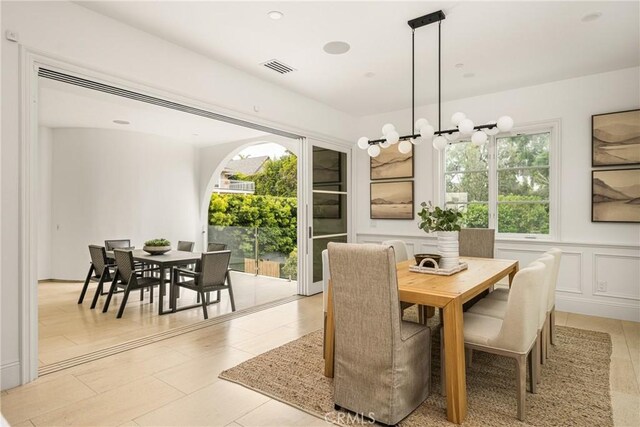 dining room with light tile patterned floors, a wainscoted wall, a notable chandelier, and visible vents