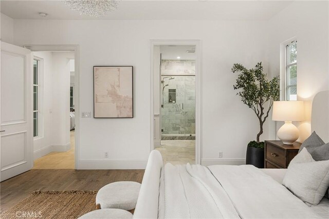 bedroom with light wood-type flooring, connected bathroom, and baseboards