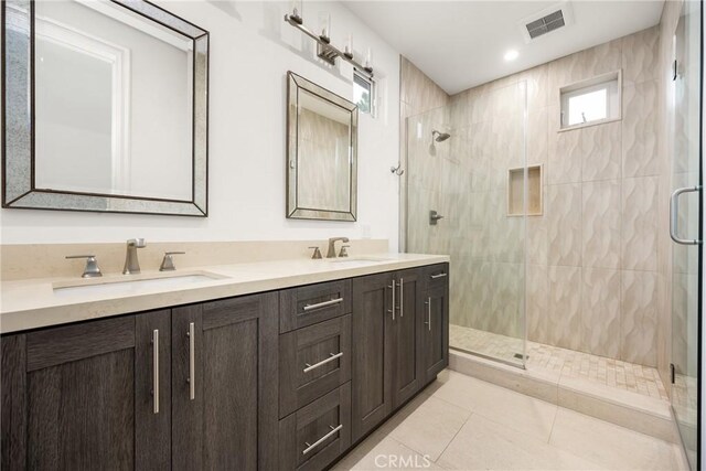 bathroom featuring a sink, a stall shower, double vanity, and visible vents