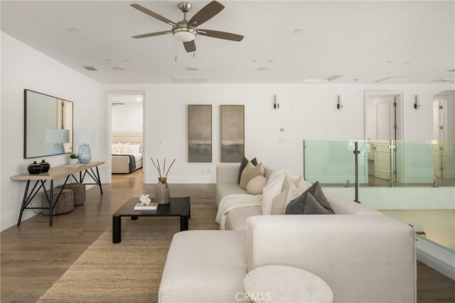 living area with baseboards, ceiling fan, wood finished floors, and visible vents