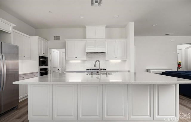 kitchen with double oven, visible vents, freestanding refrigerator, and white cabinetry