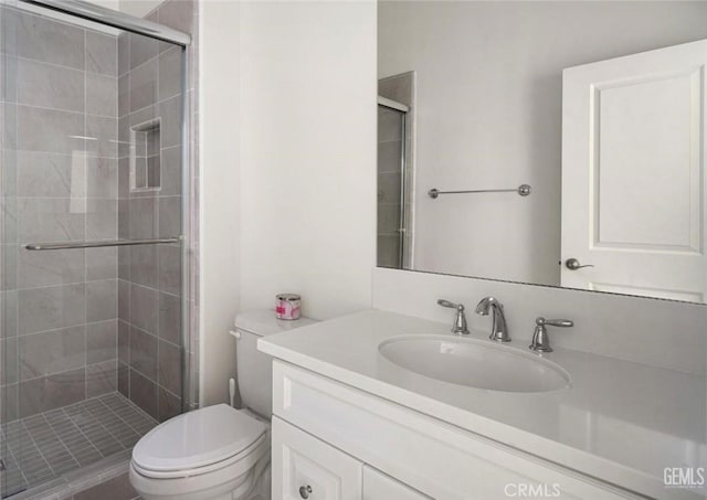 bathroom with a shower stall, toilet, and vanity