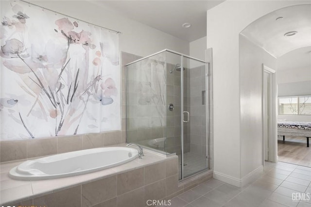 bathroom featuring tile patterned floors, baseboards, a shower stall, and a garden tub