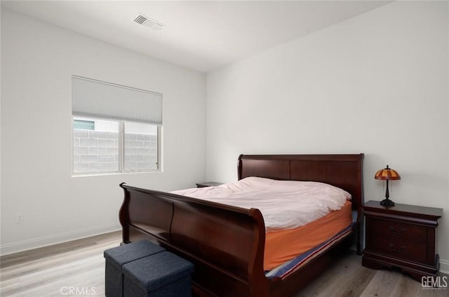 bedroom with wood finished floors, visible vents, and baseboards