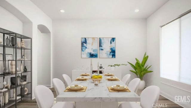 dining space with recessed lighting, arched walkways, wood finished floors, and baseboards
