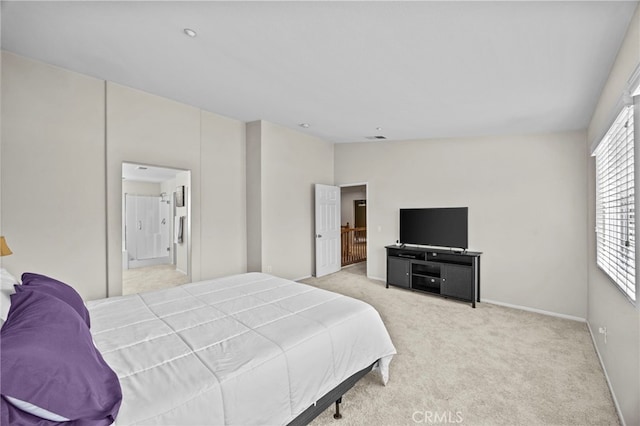 bedroom featuring baseboards, light colored carpet, visible vents, and ensuite bath