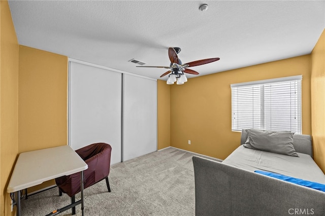 carpeted bedroom with a closet, a ceiling fan, and visible vents