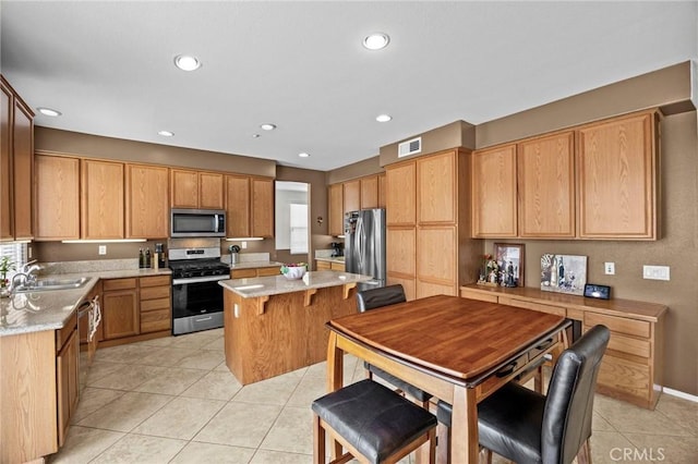 kitchen featuring visible vents, light tile patterned flooring, a center island, a sink, and stainless steel appliances