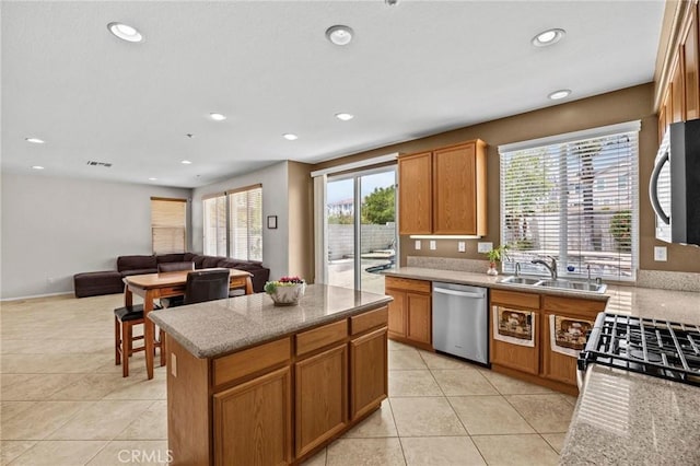 kitchen with a sink, appliances with stainless steel finishes, light tile patterned flooring, and a wealth of natural light