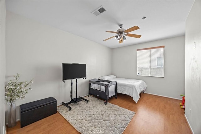 bedroom with baseboards, a ceiling fan, wood finished floors, and visible vents