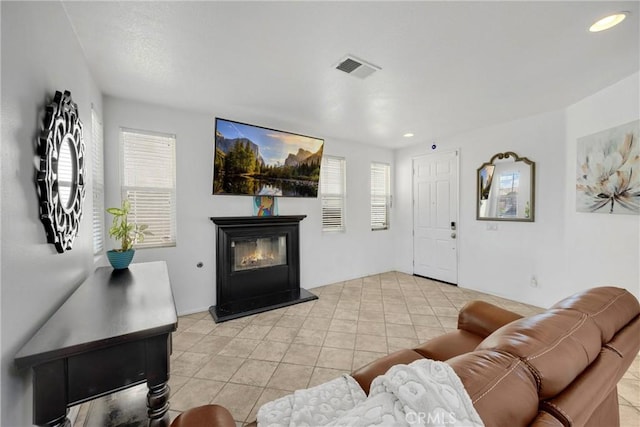 living room with a glass covered fireplace, visible vents, recessed lighting, and light tile patterned flooring