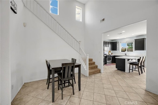 dining room with stairway, visible vents, light tile patterned flooring, recessed lighting, and a high ceiling