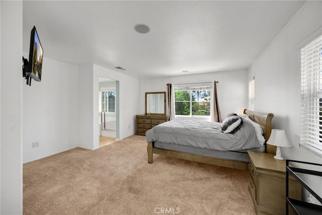 bedroom with visible vents, connected bathroom, and light carpet