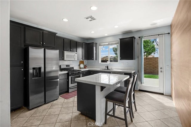 kitchen featuring stainless steel appliances, a kitchen breakfast bar, visible vents, tile countertops, and light tile patterned flooring