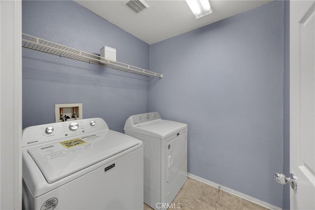 clothes washing area with washer and clothes dryer, visible vents, laundry area, and baseboards