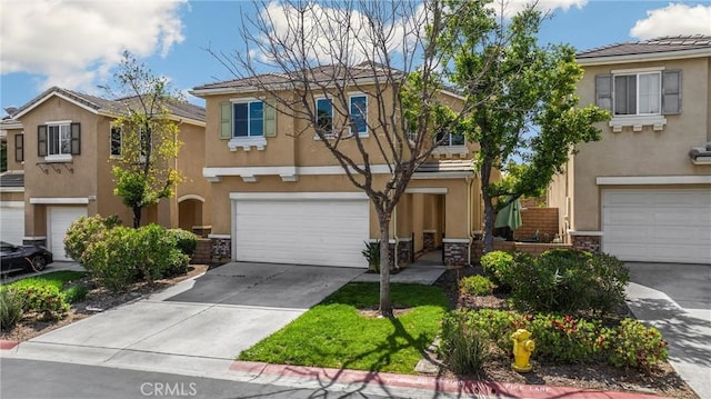 view of property with a garage, stucco siding, and concrete driveway