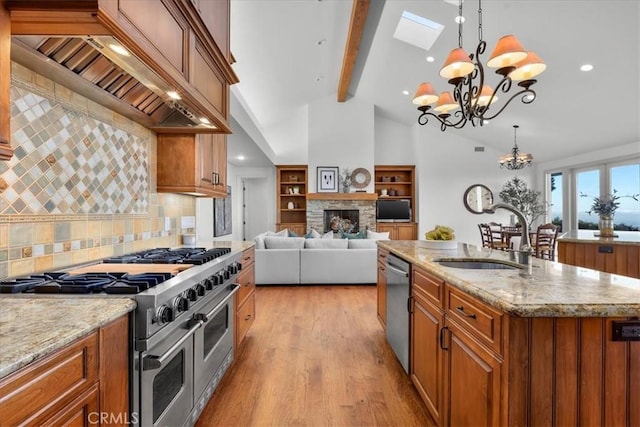 12 Bowie Rd, Rolling Hills, CA 90274 - kitchen with stainless steel appliances, a sink, wall chimney exhaust hood, brown cabinetry, and a chandelier